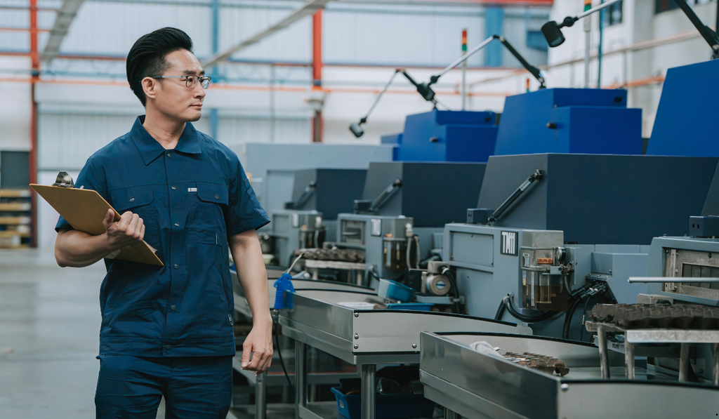 Manufacturing worker monitoring production equipment, illustrating how a pull system in Lean manufacturing responds to downstream demand and actual production needs.