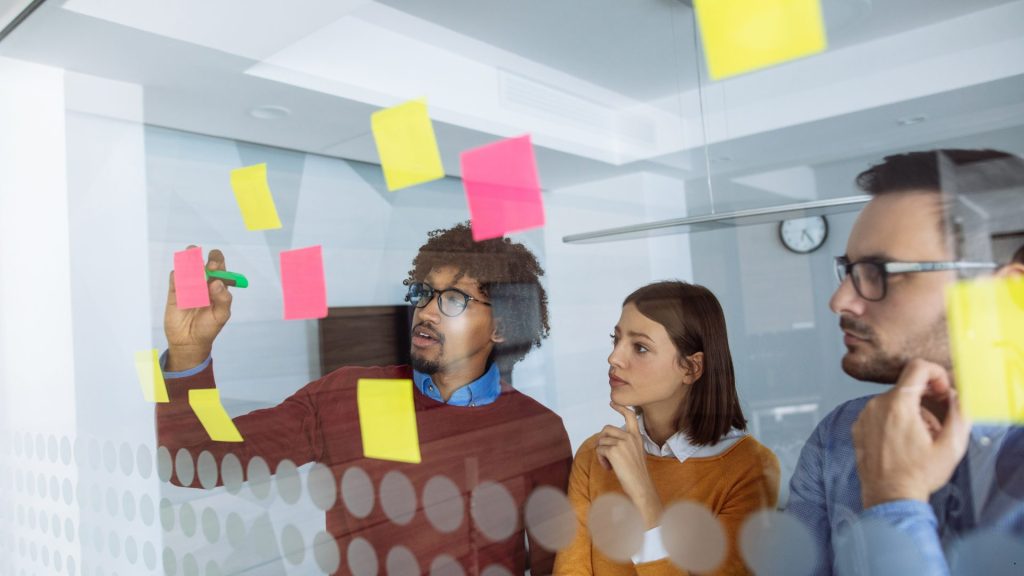 Team collaborating with sticky notes to apply the DMAIC Methodology during a process improvement workshop.