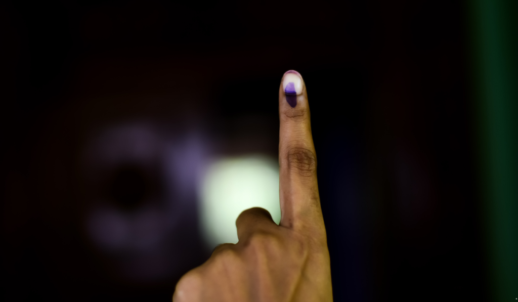 Voter showing an ink-marked finger after casting a ballot, representing EVM voting and election participation.
