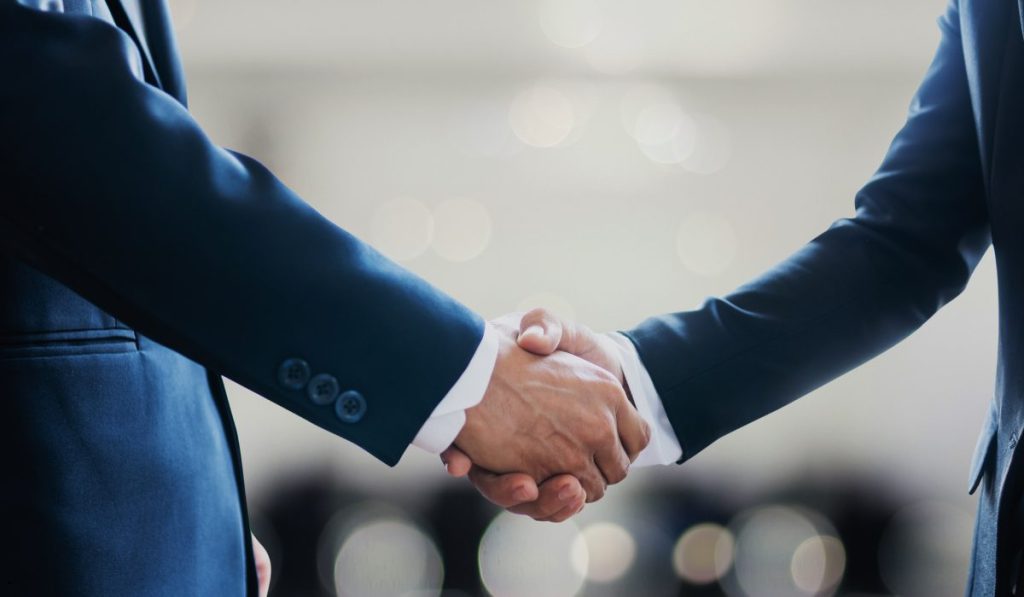 Business handshake representing control limits and collaboration to maintain consistent quality and process performance.