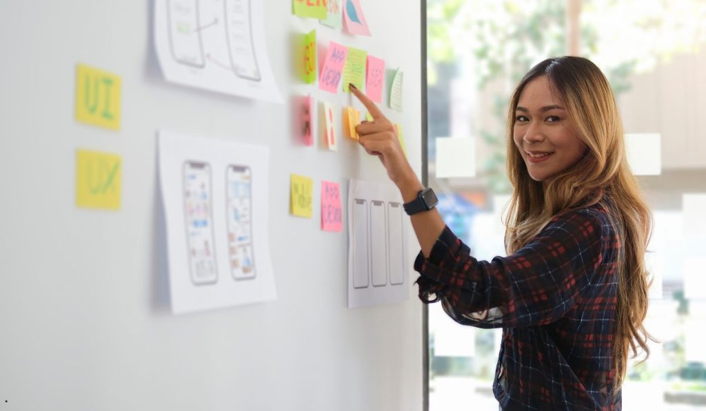 Team member using a planning board to apply DMAIC vs PDCA methodologies for structured problem-solving and workflow improvement.