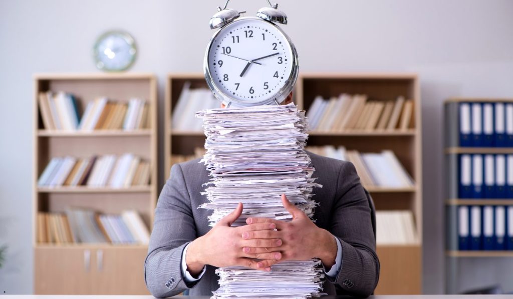Business professional managing a heavy workload, highlighting the impact of turnaround time on productivity and efficiency.