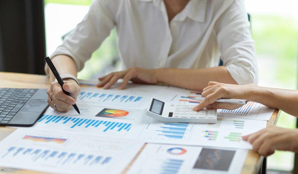 Analysts reviewing charts, reports, and calculator results to detect a lurking variable in data interpretation.