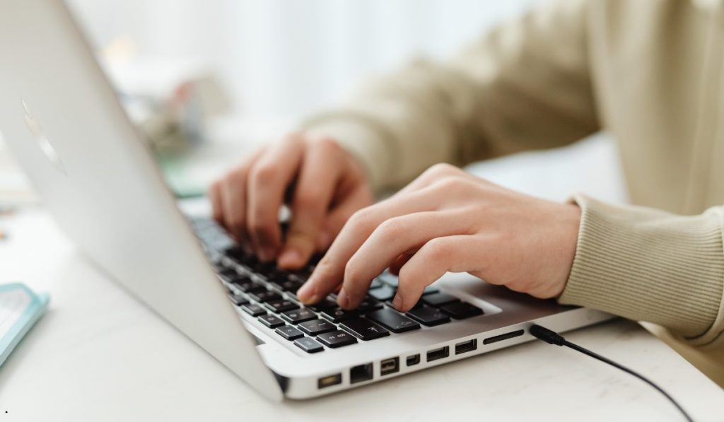 Close-up of hands typing on a laptop while building a Probability Plot Excel worksheet for statistical evaluation.