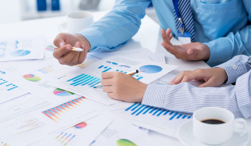Business professionals discussing statistical reports that demonstrate the Sample Mean Symbol and data trends.
