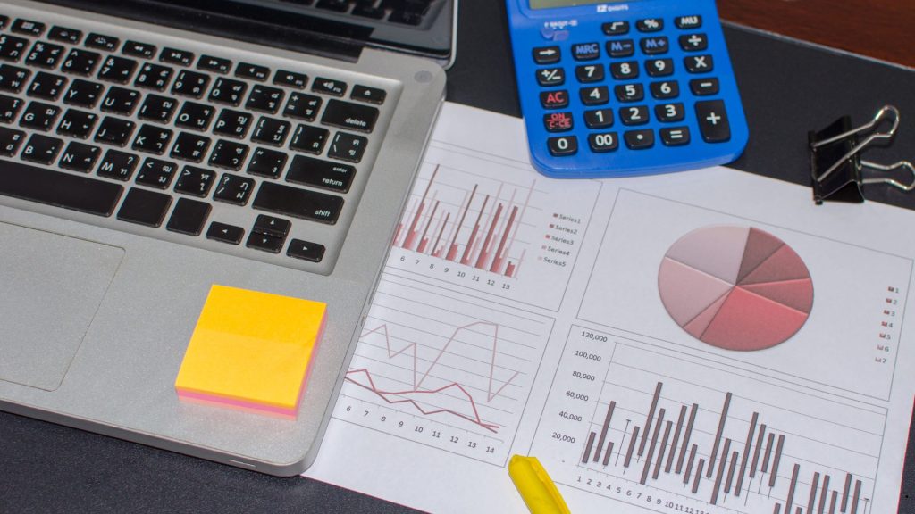 Financial reports with graphs, calculator, and laptop demonstrating coefficient of variation meaning for measuring relative data dispersion and consistency.