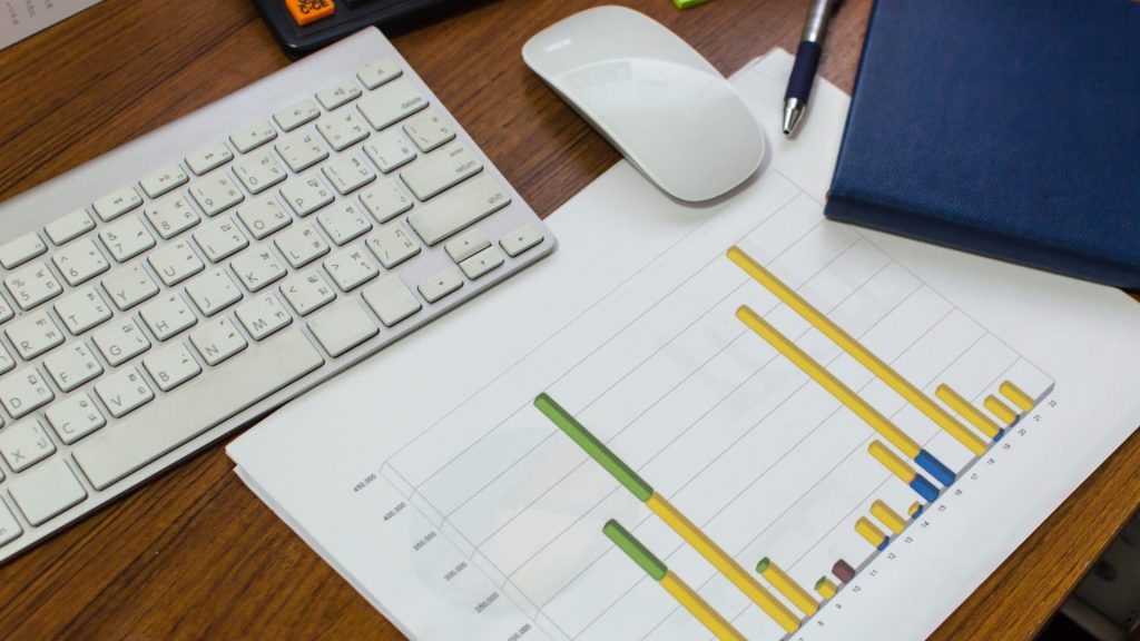 Business workspace with bar chart reports and computer accessories illustrating coefficient of variation meaning in data comparison and variability analysis.