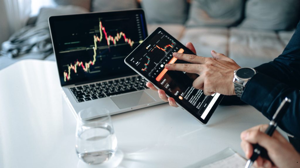 Person analyzing financial charts on a tablet and laptop to understand the coefficient of variation meaning in investment performance and risk assessment.
