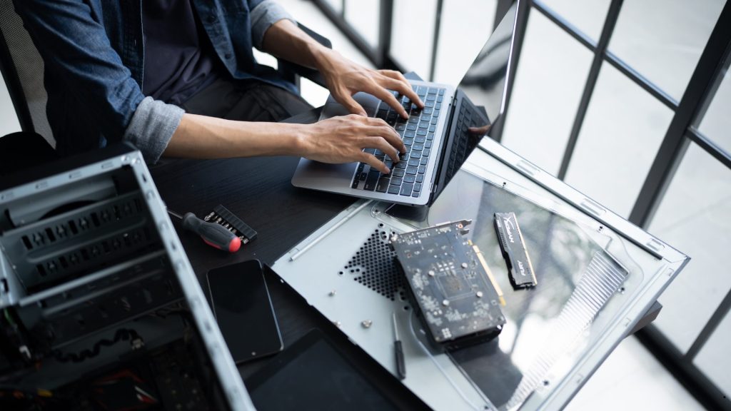 Professional analyzing system requirements and technical data using a laptop as part of a Feature Prioritization Matrix assessment.