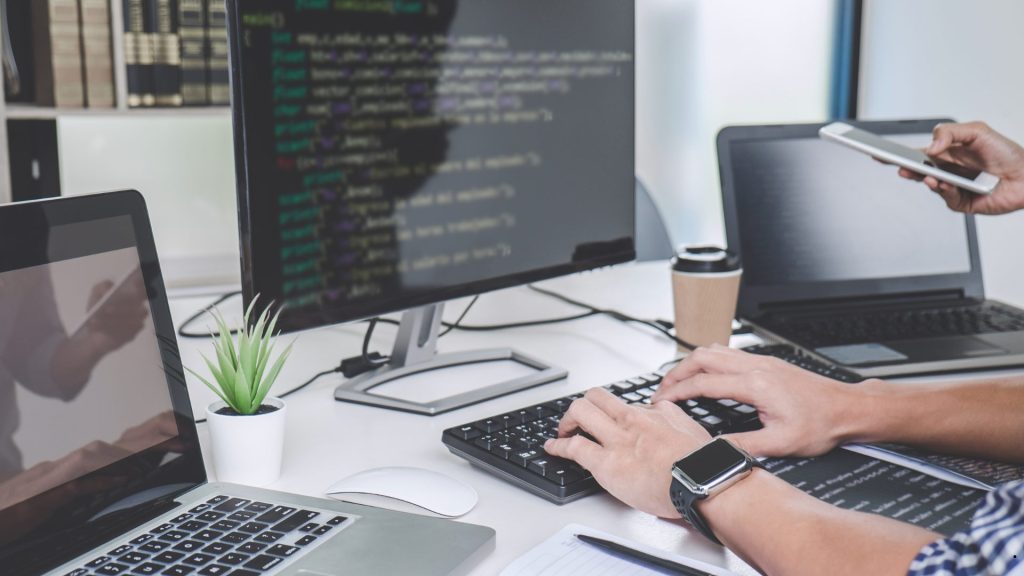 Developer analyzing software code and statistical outputs on multiple devices to understand SE vs SD for data-driven decision-making.