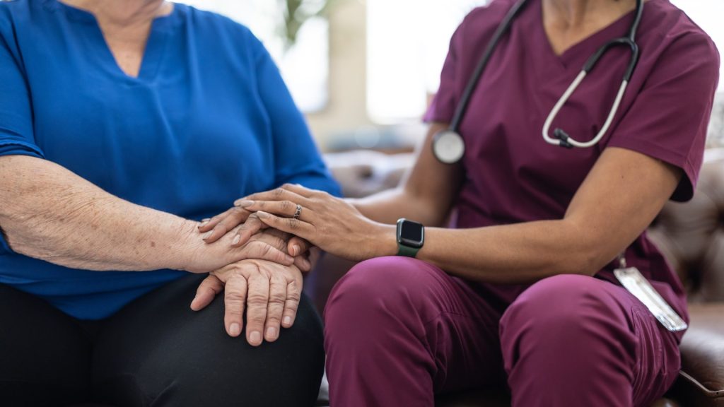Nurse providing compassionate patient support and care coordination as part of Six Sigma healthcare excellence and patient-centered outcomes.