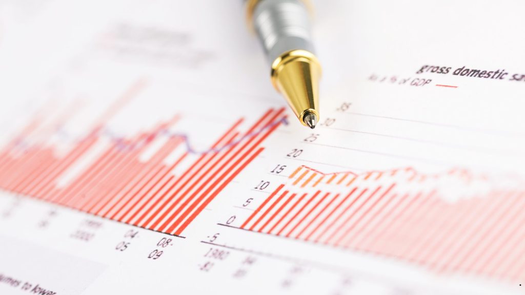 Skewed to the right histogram analysis with a financial chart and pen highlighting a distribution with a long right tail.