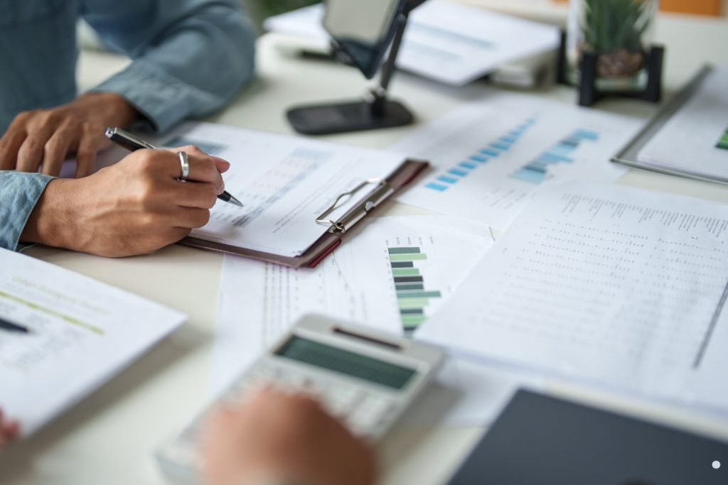 Business professionals reviewing reports, charts, and financial documents during a Continuous Quality Improvement analysis and performance evaluation meeting.