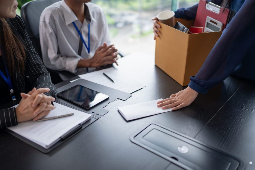 Employee handing over a resignation envelope in an office for a letters of recommendation sample topic.