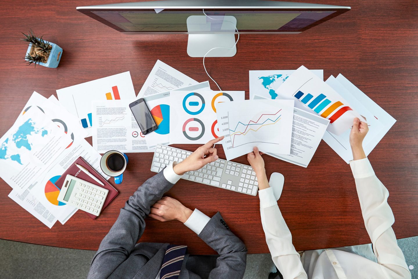 Problem solving process business analysis meeting with charts, reports, and performance data on an office desk.