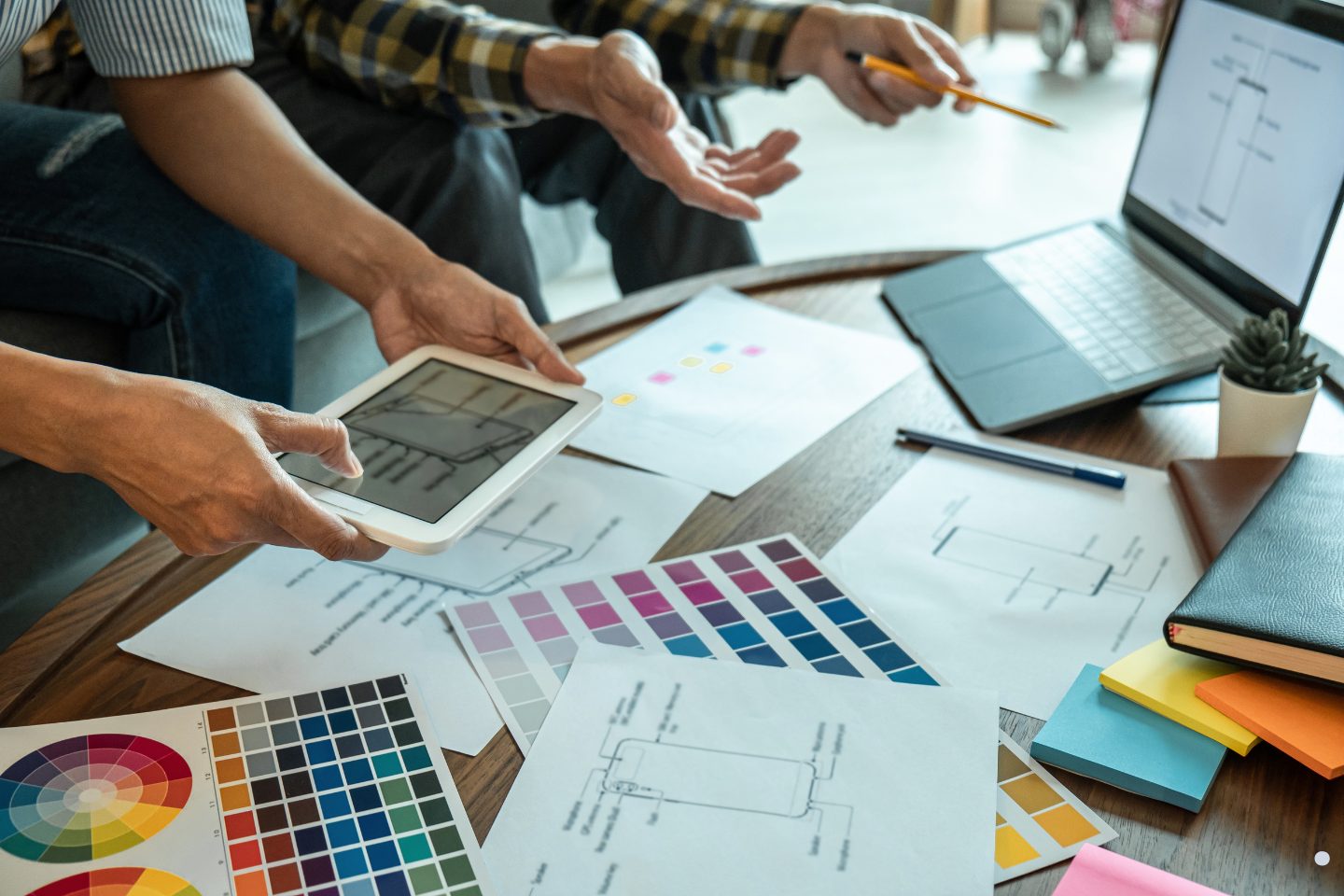 Creative professionals analyzing design layouts and planning documents within a Project Management Framework workshop.