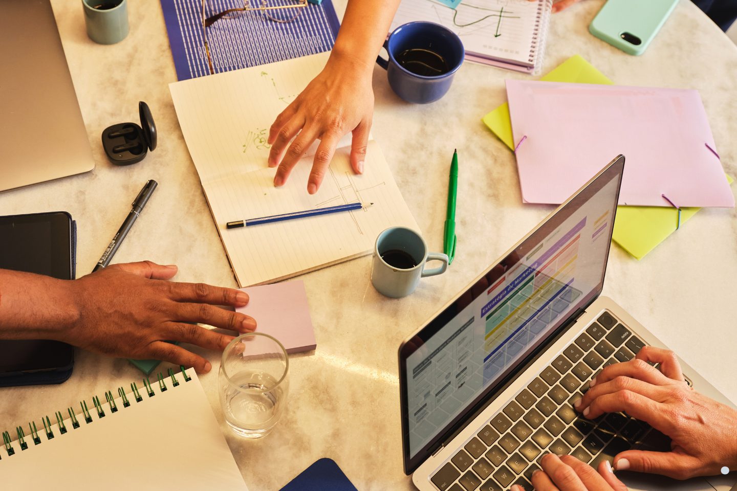 Team members collaborating with laptops, notes, and workflow diagrams during a Project Management Framework strategy meeting.