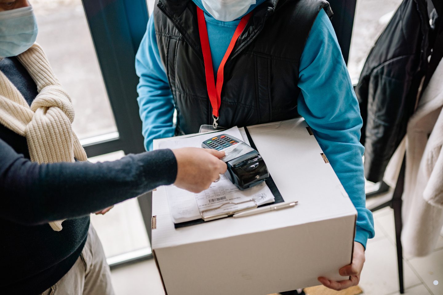 Delivery personnel processing a contactless payment transaction while handing over a customer package at the doorstep.