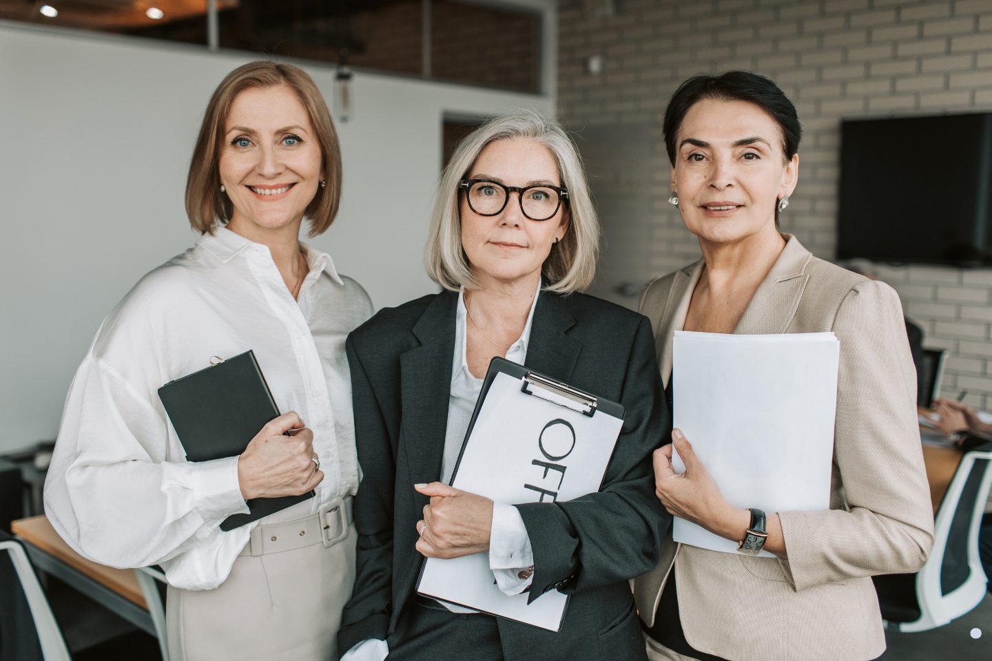 Experienced business professionals holding documents and leadership materials in a corporate environment.