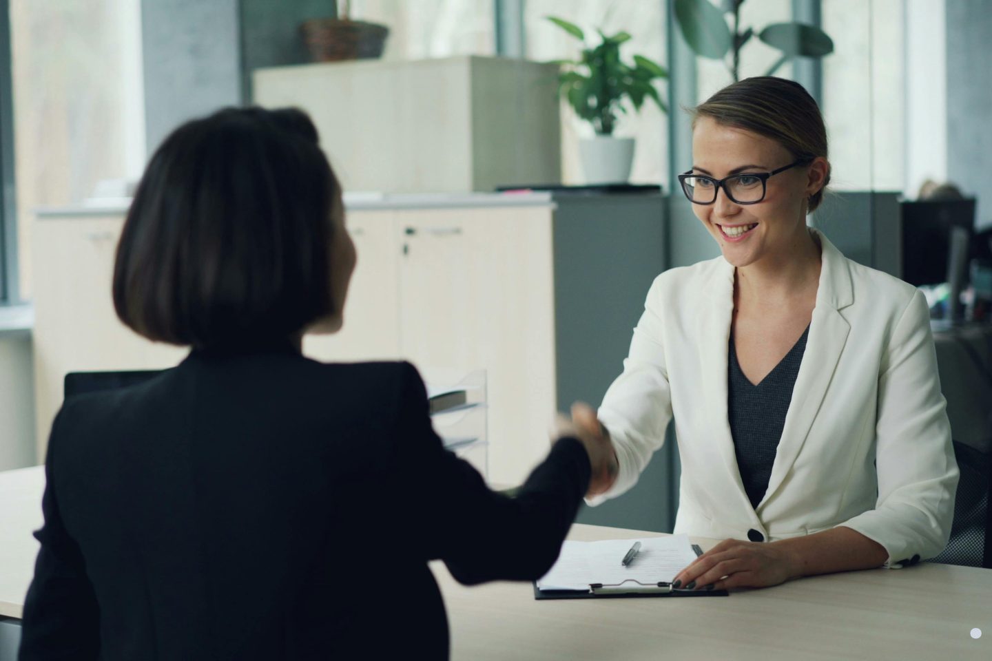 Professional business consultant shaking hands with a client during a corporate leadership meeting.