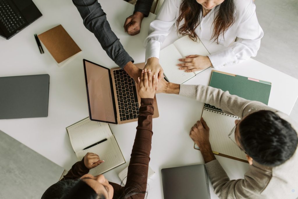 Team members stacking hands together during a collaborative business meeting focused on teamwork and organizational success.