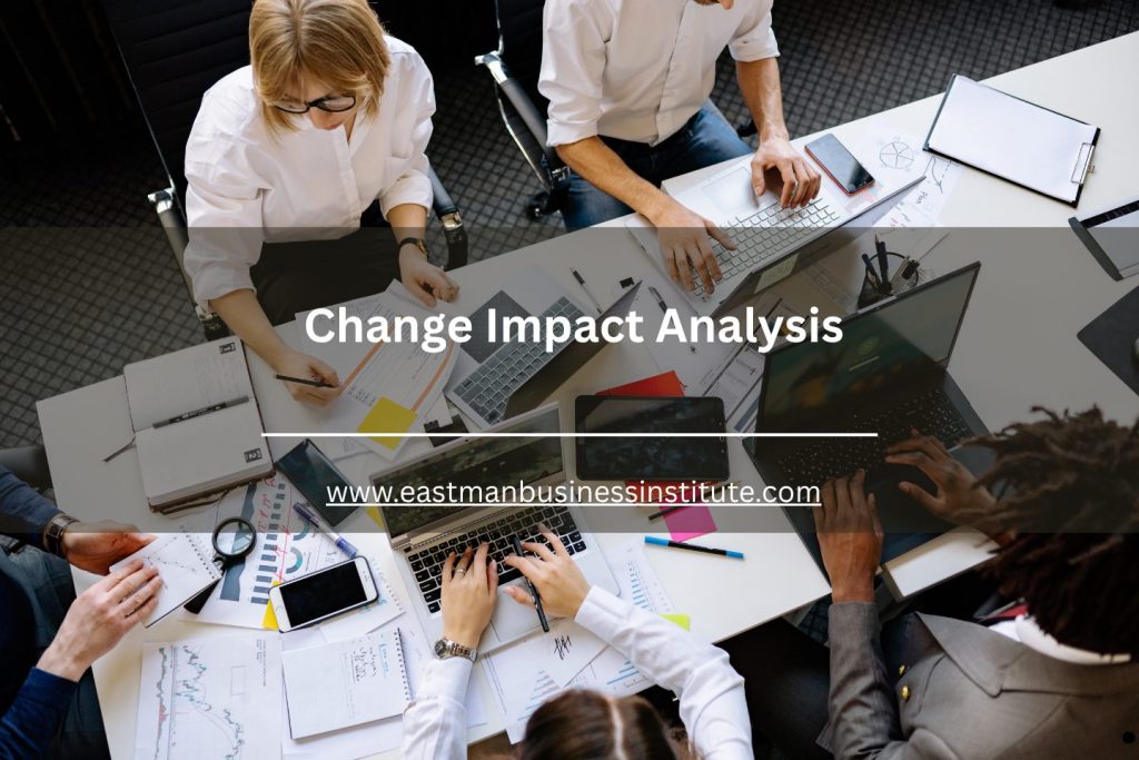 Top view of team collaborating on laptops and documents with change impact analysis overlay on screen