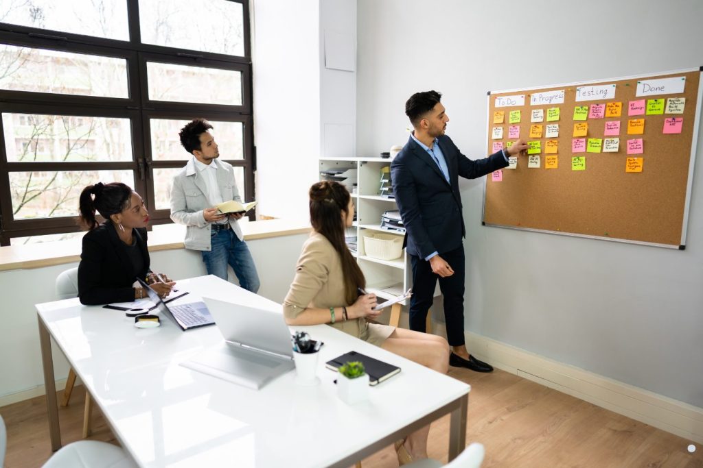 Business team reviewing workflow tasks and project progress using a Kanban board during a planning meeting.