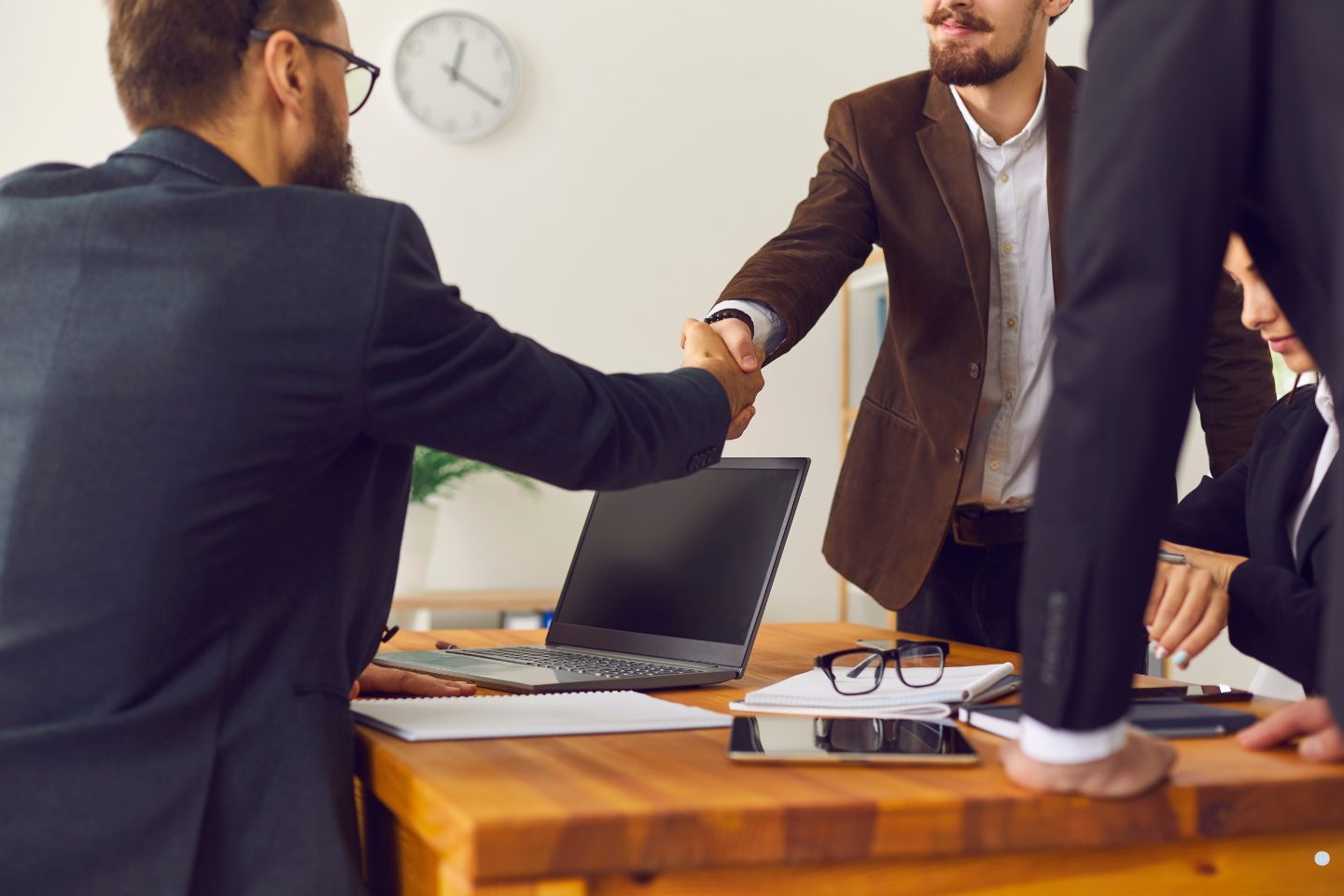 Business professionals shaking hands across a conference table during a corporate meeting and partnership discussion.