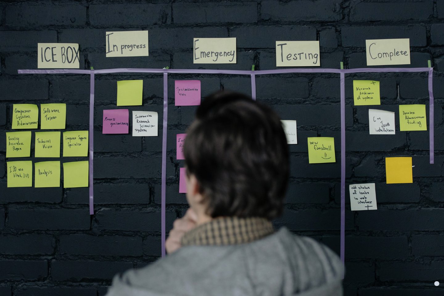 Project manager reviewing workflow tasks and sticky notes on an agile planning board