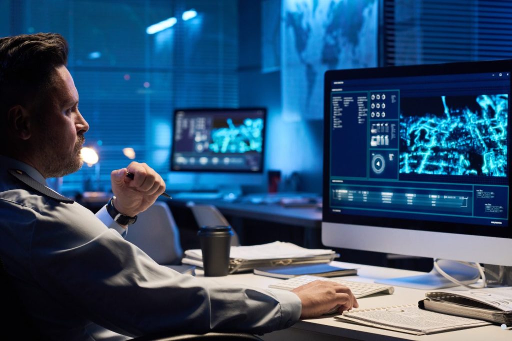 Analyst reviewing digital dashboards and data visualizations on multiple computer screens in a modern office