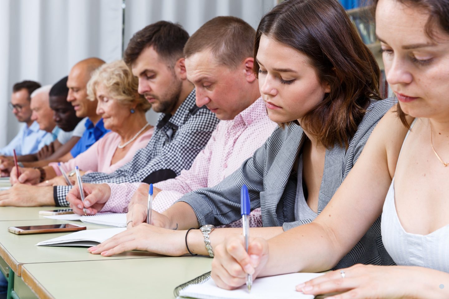Participants sitting in a row taking notes during a training session or workshop.